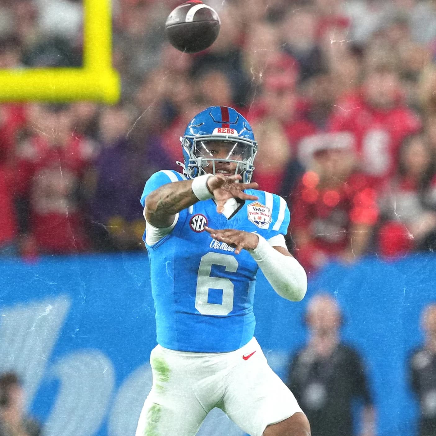 An Ole Miss quarterback in powder blue fires a pass against a red-clad crowd.