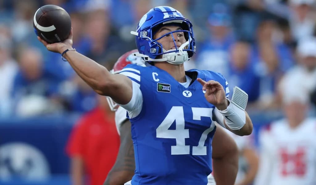 BYU quarterback throws a deep ball in blue home uniform