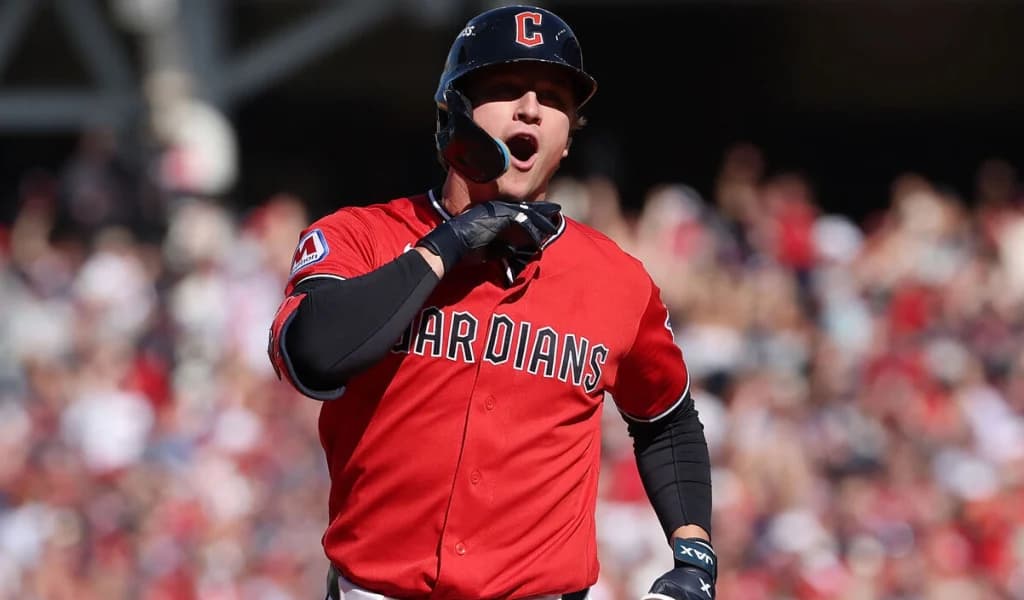 A Cleveland Guardians hitter in the red alternate jersey shouts in celebration.