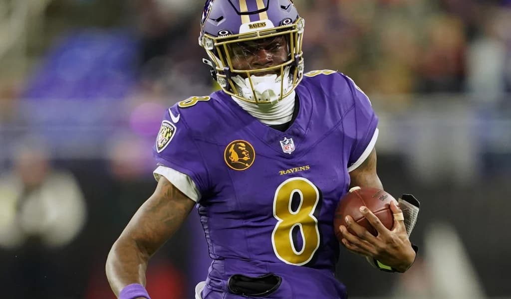 Lamar Jackson of the Baltimore Ravens runs with the ball in the purple home uniform.