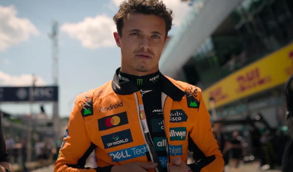 Lando Norris in his orange McLaren race suit in the paddock.